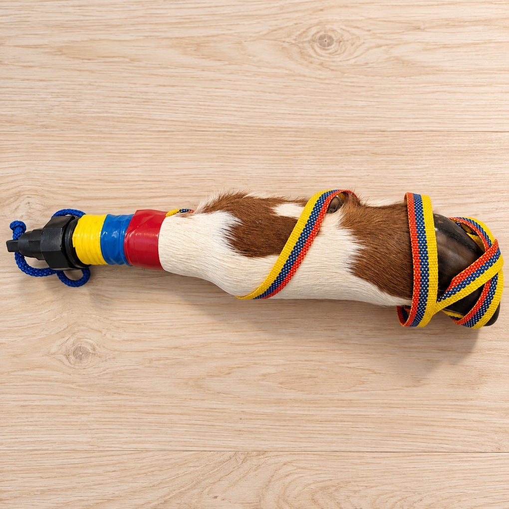 Handcrafted cowhide hoof bottle with yellow blue and red strap on light wood table