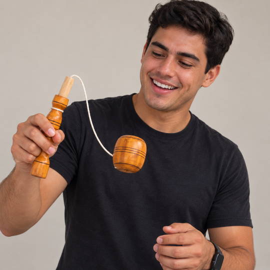 Young man playing with a traditional Colombian balero against a neutral background
