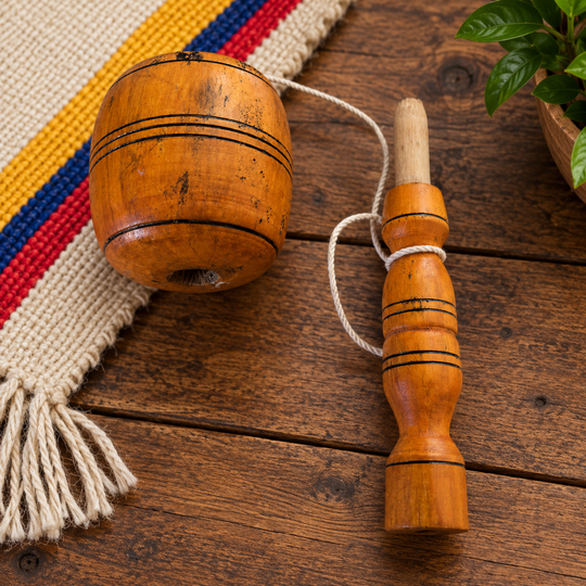Traditional Colombian balero with cup and handle separated on a rustic table