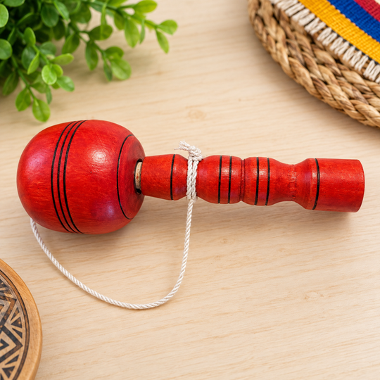 Traditional Colombian red coca wooden cup-and-ball toy on a light table